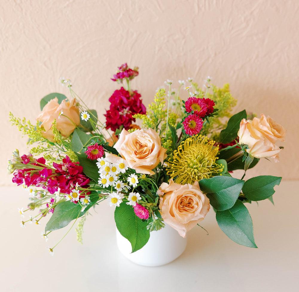 Vibrant fuschia stock and china aster with pale roses, solidago and pincushion protea