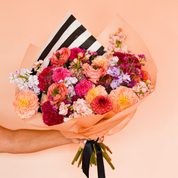 Blossom's luxe bouquet is available for delivery and includes premium multicolored stems wrapped in peach tissue and tied with a satin ribbon