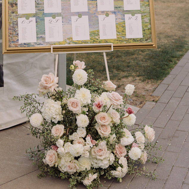 A gorgeous arrangement sits under a seating chart and a wedding