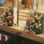 Two multi-colored statement pieces flank an altar at a wedding designed by Blossom's floral designers