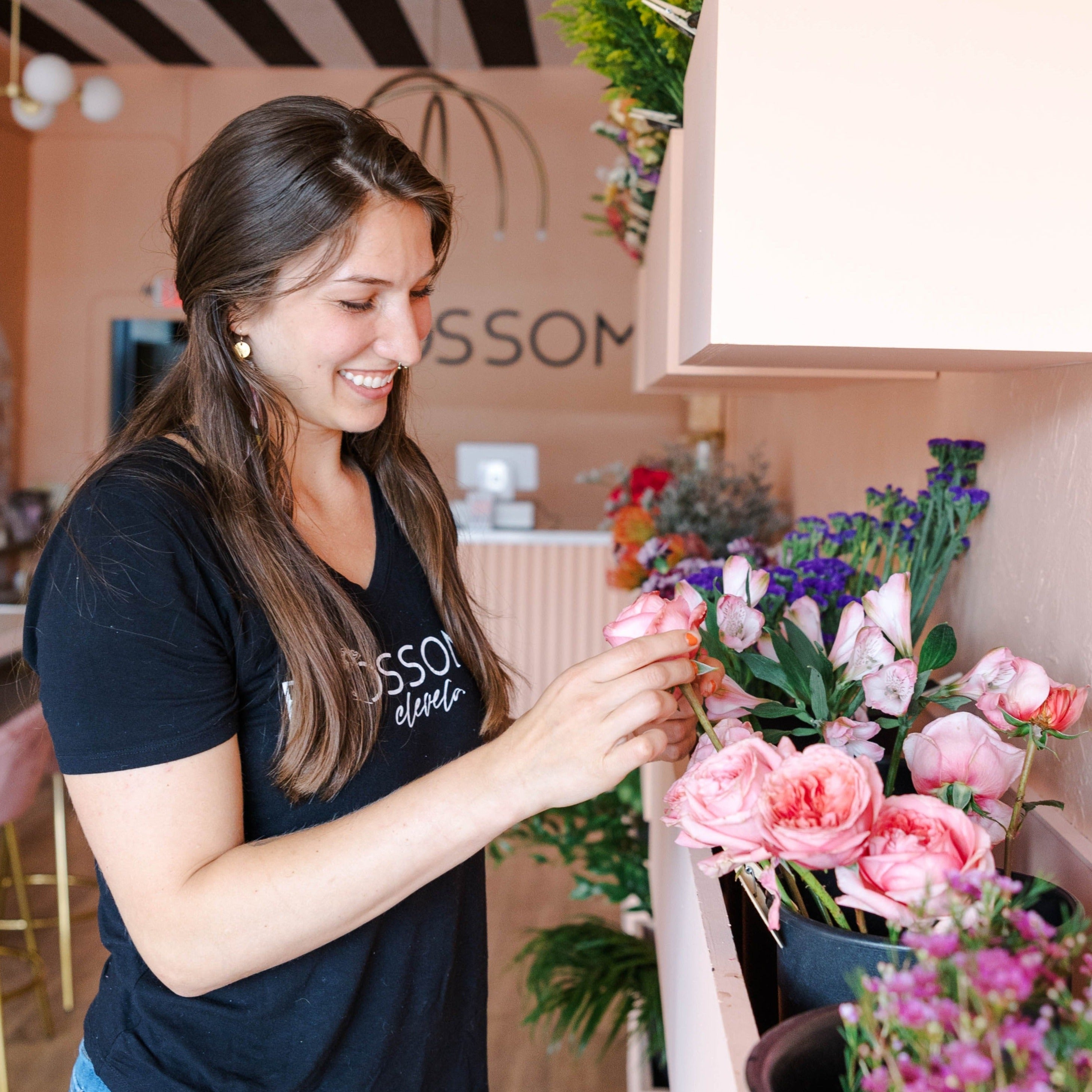 A Blossom Team member takes a closer look at a rose in the fully stocked Flower Bar