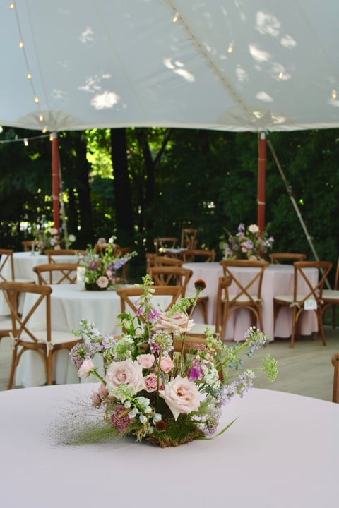 custom wedding centerpieces include moss in a tented backyard reception