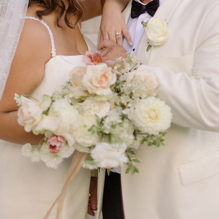 a bride and groom hold onto a bouquet of wrapped stems for their wedding in Cleveland
