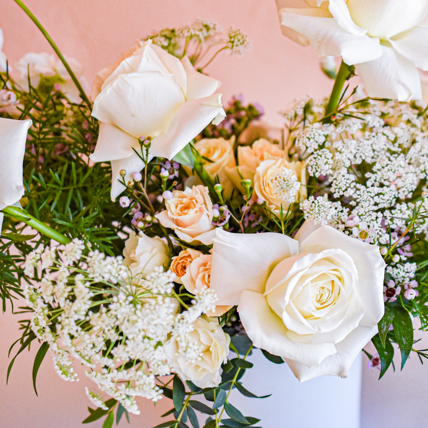floral designers pair white roses, pale peach spray roses, purple waxflower, Queen Anne's Lace and greens
