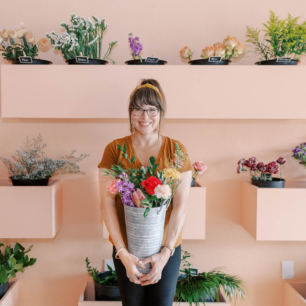 happy customer standing in front of a wall of flowers