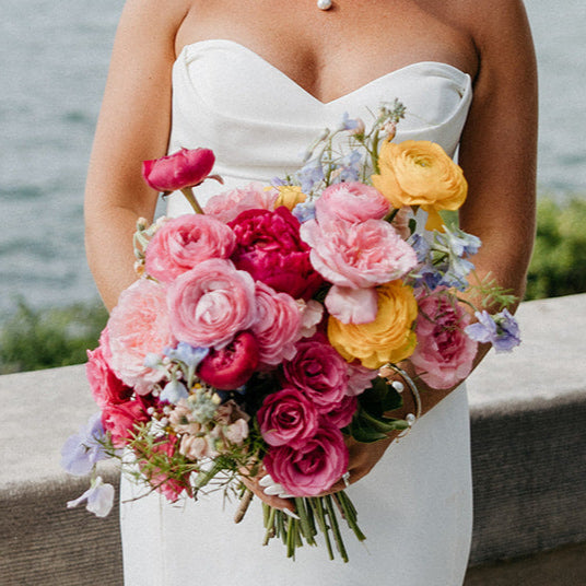 pink dahlias, coral peonies, yellow ranunculus create a colorful bridal bouquet from Blossom Flower Bar