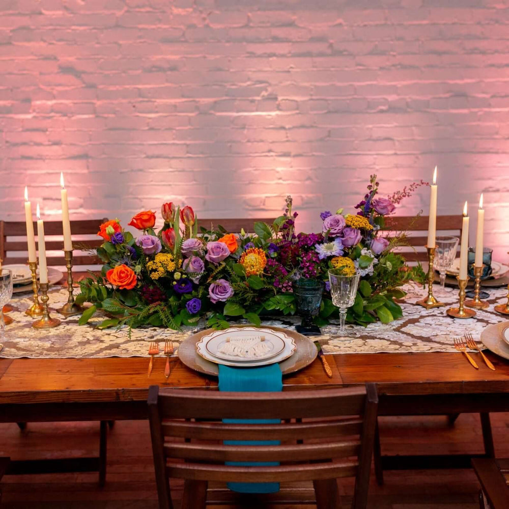 Colorful long low centerpiece on wood table with white brick wall background