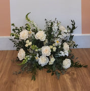 A statement piece of bright white roses, tulips and snapdragons is paired with deep greens and can be used for both the ceremony and reception
