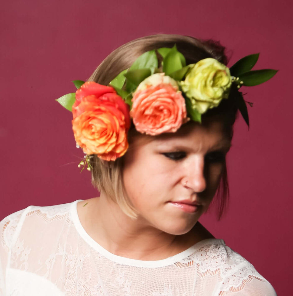 Woman wearing bold flower crown with orange and yellow flower with greens and baby's breath
