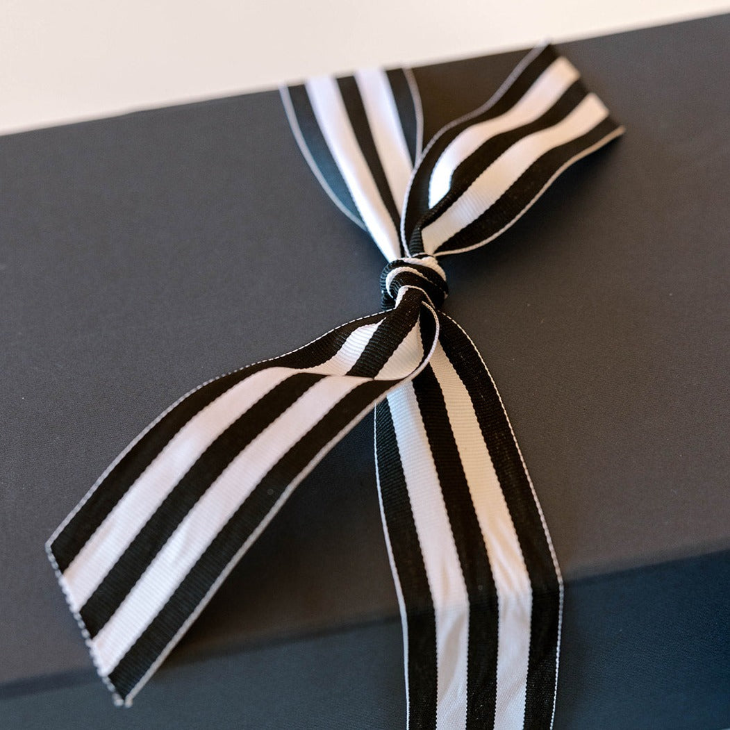 an elegant gift with a black and white ribbon tied on a black box