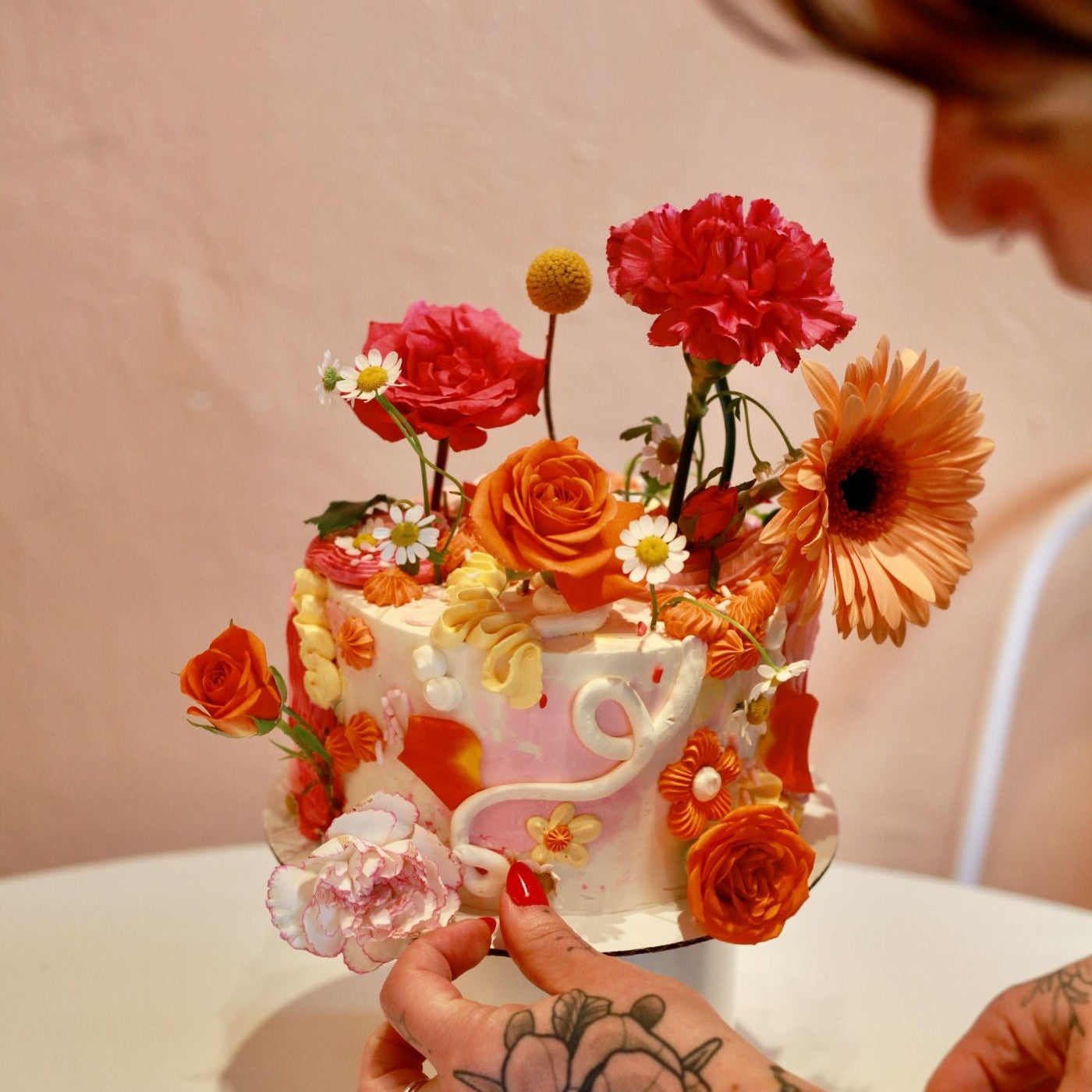 Person arranging flowers on a decorated cake