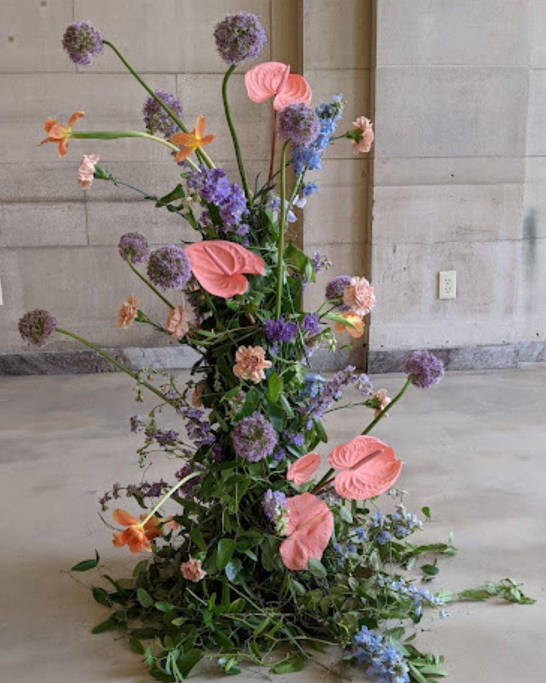 A tall, sculptural flower arrangement including allium, anthurium and tulips
