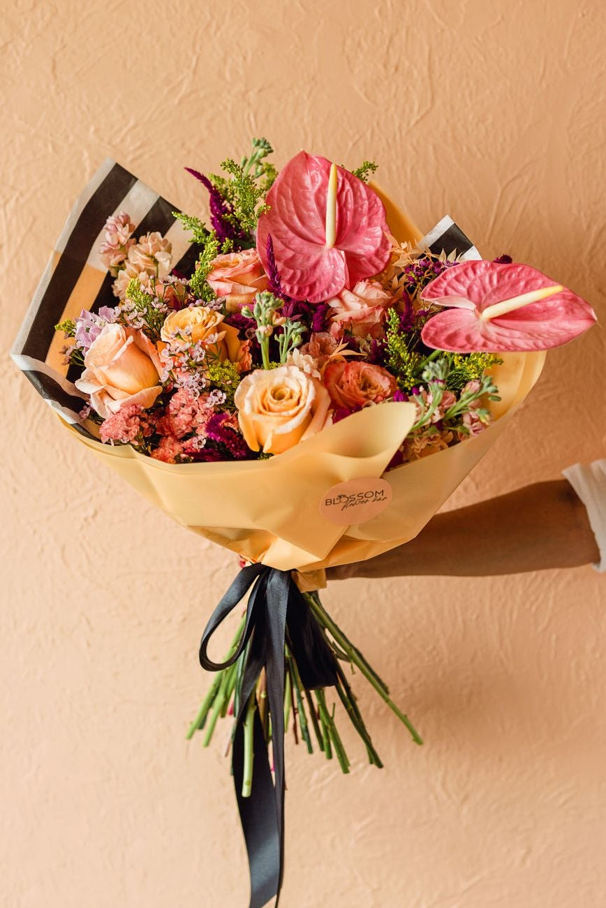 A vibrant flower wrap with roses, anthurium and other fresh stems