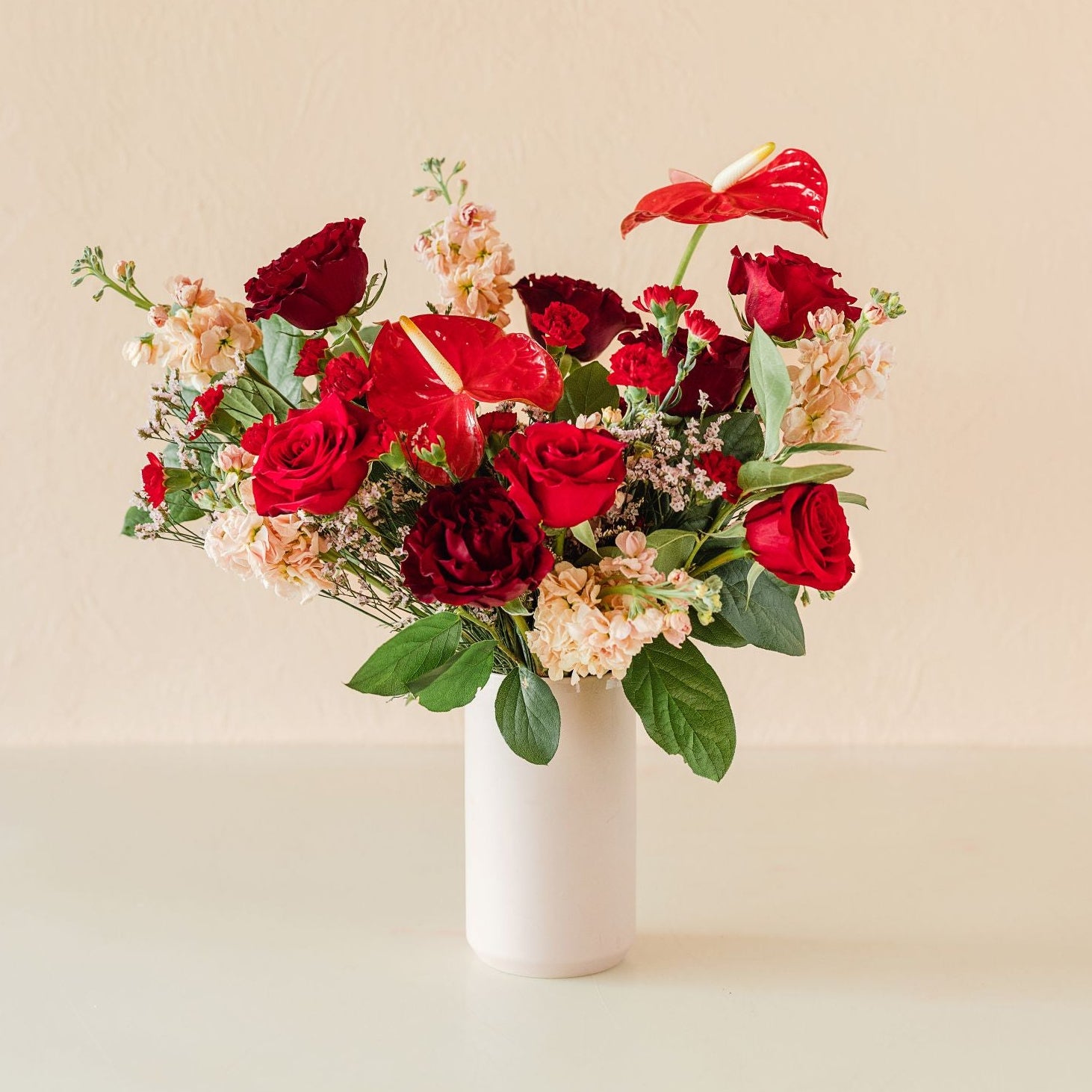 A large vase overflowing with bright flowers in shades of red