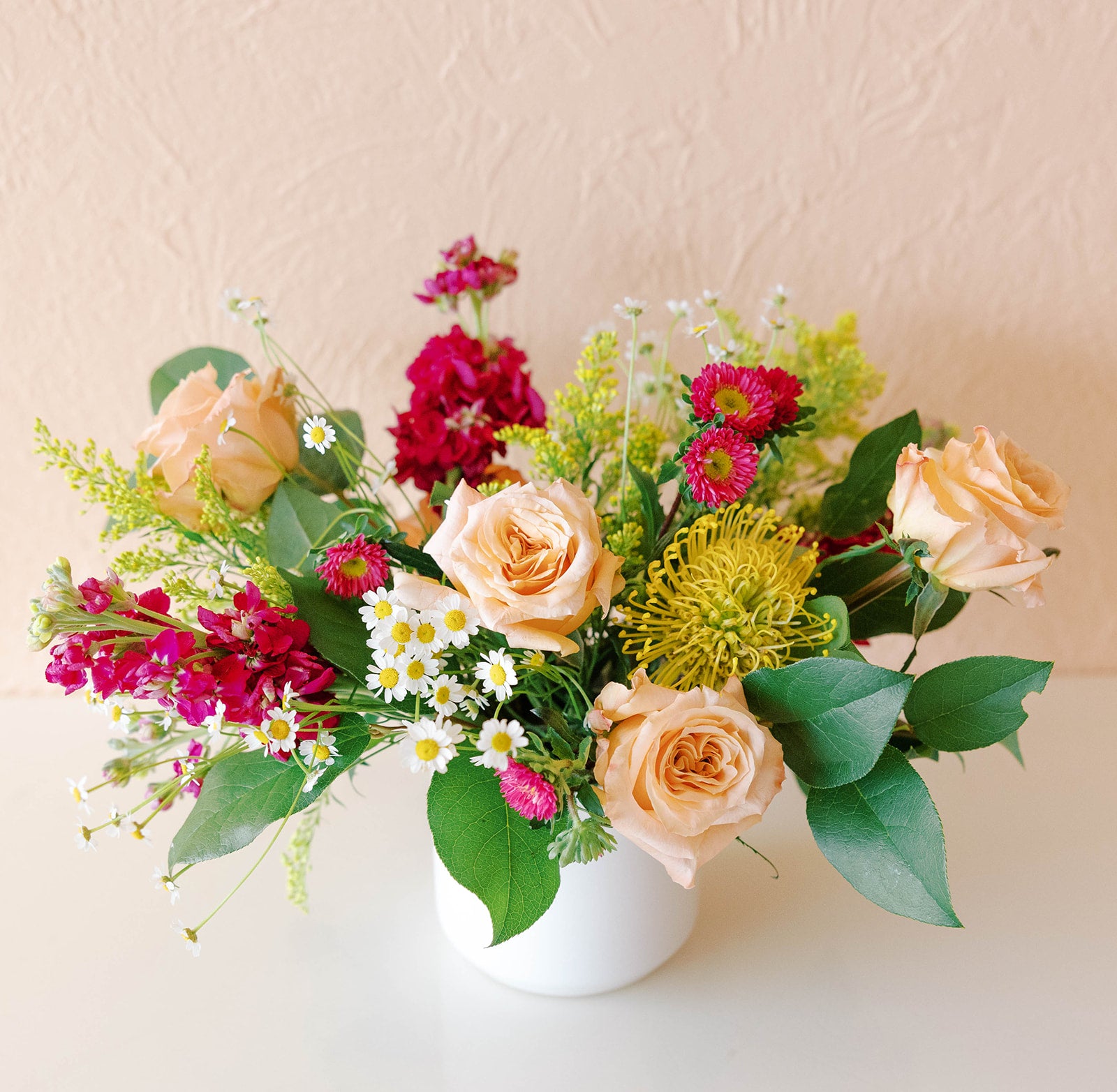 Vibrant fuschia stock and china aster with pale roses, solidago and pincushion protea make the perfect gift for delivery or pickup
