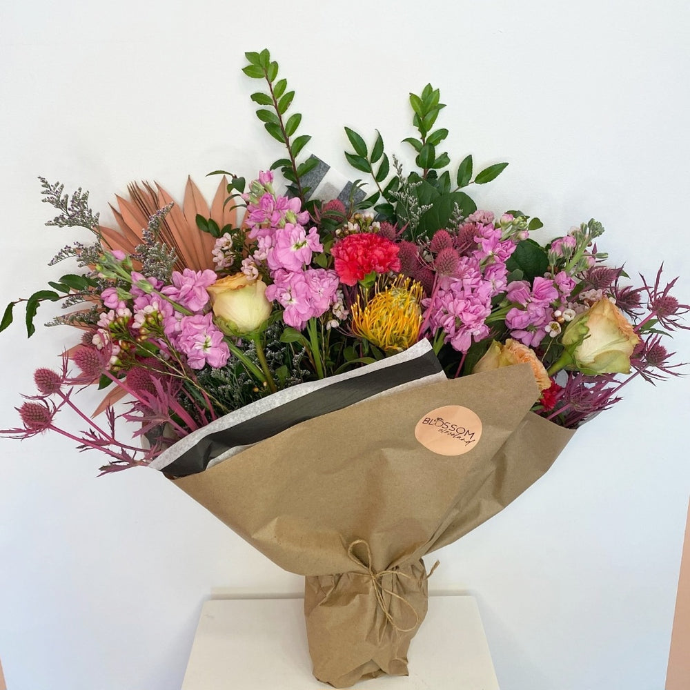Purple, pink and yellow blooms in a large bouquet wrapped with kraft paper