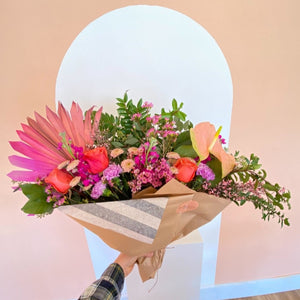Eclectic arrangement of flowers with anthurium and palm leaf