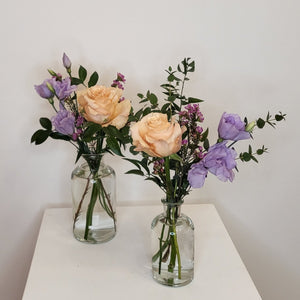 two bud vases with peach and purple blooms